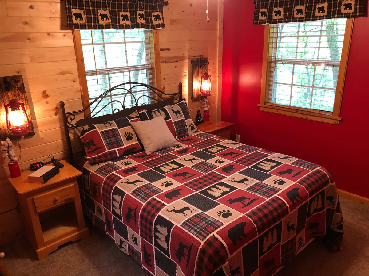 This image presents a cozy bed dressed with a patterned blanket, lanterns providing gentle lighting, and warm wooden walls. The natural light filtering through the windows suggests a soothing environment ideal for rest or reading, aligning perfectly with the theme of relaxation and retreat.