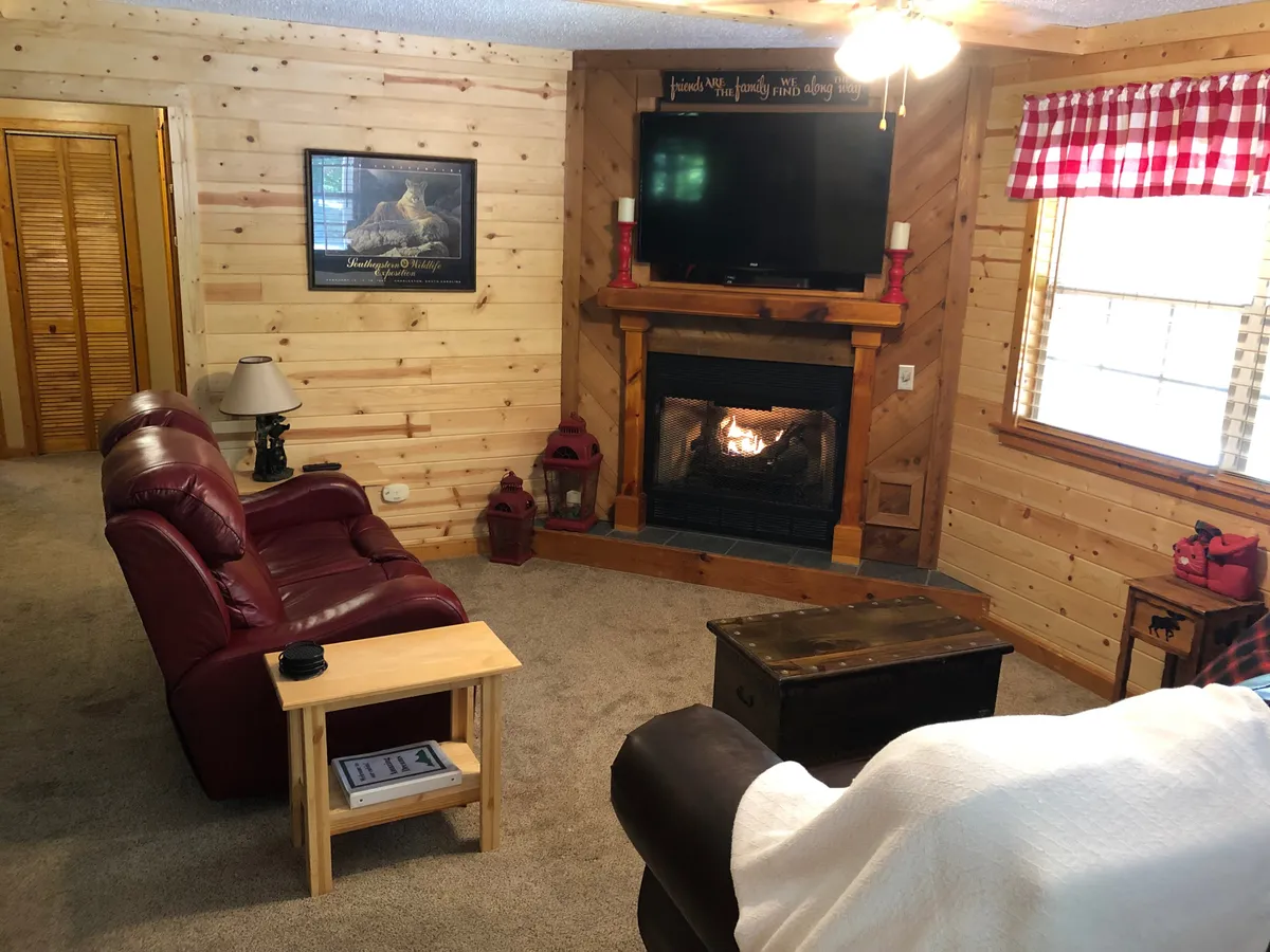The heart of the living space with a plush sofa facing a glowing gas fireplace, a coffee table, TV, and welcoming artwork. The fireplace is a central feature, ideal for gathering or relaxing on chilly evenings.